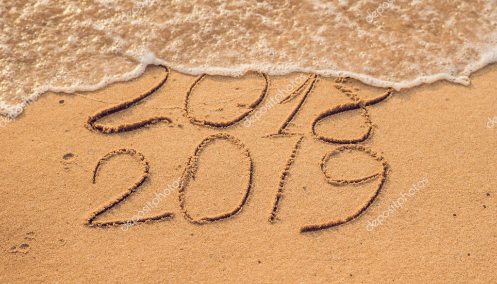 New Year 2019 is coming concept - inscription 2018 and 2019 on a beach sand, the wave is almost covering the digits 2018