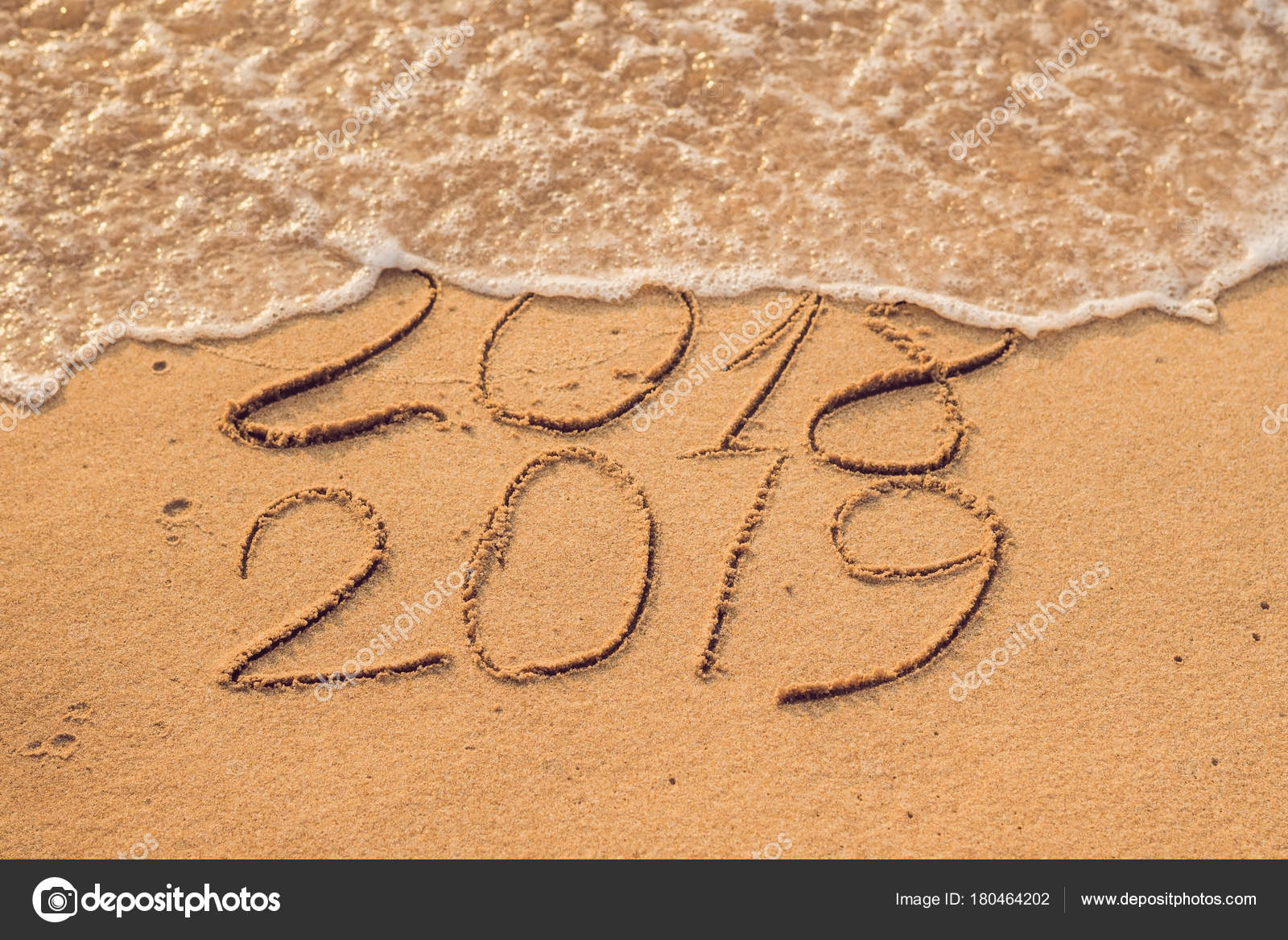 New Year 2019 is coming concept - inscription 2018 and 2019 on a beach sand, the wave is almost covering the digits 2018